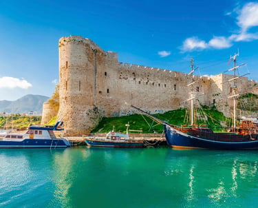Historic Kyrenia Castle and wooden sailboats in the turquoise water of the old harbor in Northern Cyprus.
