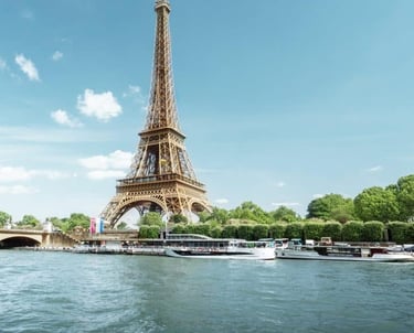The Eiffel Tower stands tall over the Seine River in Paris with tourist boats docked nearby.
