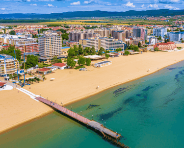 Aerial view of Sunny Beach, Bulgaria, showing a bustling sandy beach, turquoise Black Sea, and a pier extending into the