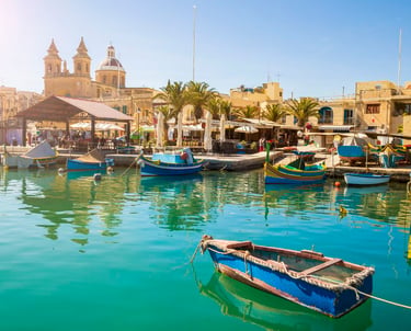Colorful Luzzu fishing boats in Marsaxlokk village harbor, Malta, on a sunny day.