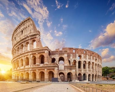 Sunset over the Roman Colosseum with a golden sky and wispy clouds in Rome, Italy.
