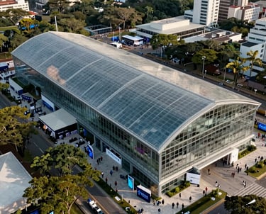 An aerial shot of a large tech conference held in a modern glass pavilion in São Paulo, showing the layout from above. Clean and professional.