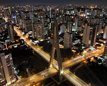 A stunning aerial view of the Octávio Frias de Oliveira Bridge in São Paulo at night, showing the lights and the city traffic. High-end professional drone photography.