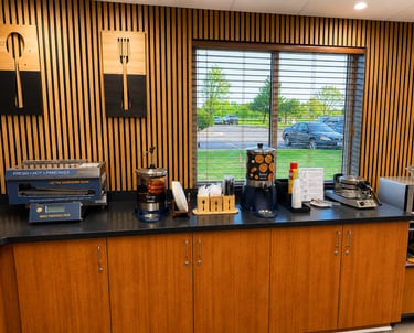 Hotel breakfast bar with an automatic pancake machine, syrup, butter, and waffle makers.