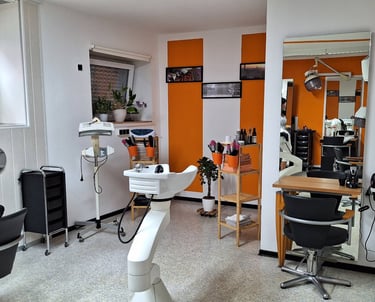 Modern hair salon interior with orange accents, styling stations, and professional shampoo sinks.