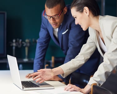 a man and woman looking at a laptop computer
