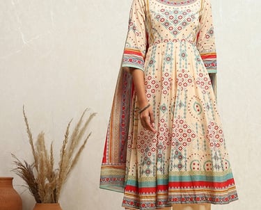 Woman wearing a beige printed Anarkali suit with palazzo pants and a red dupatta.