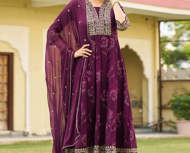 Woman wearing a purple Anarkali suit with gold embroidery and a matching sheer dupatta.