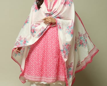 Woman wearing a pink printed cotton kurti with floral dupatta and white palazzo pants for ethnic style.