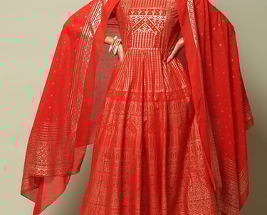 Elegant woman wearing a red and gold ethnic Anarkali suit with a matching dupatta and churidar.