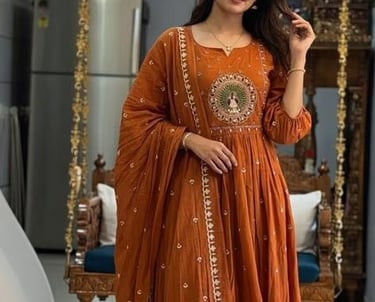Woman wearing an elegant rust orange Anarkali suit with traditional Indian embroidery.