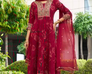 Woman wearing a maroon embroidered Anarkali suit with gold zari work and matching dupatta.