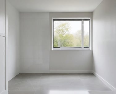 Minimalist empty room with white walls, grey tile flooring, and a large window showing green trees.