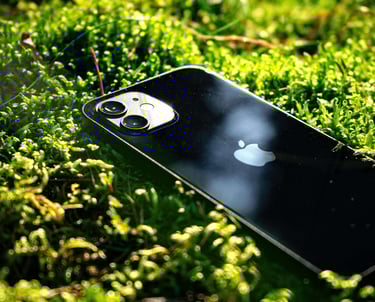 iPhone Km0 negro sobre musgo verde, destacando la sostenibilidad y la integración de la tecnología con la naturaleza.