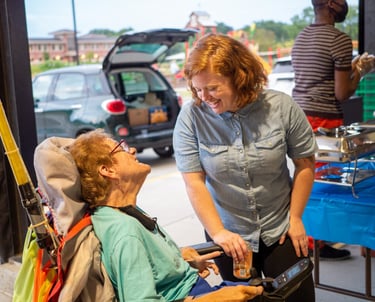 Person in wheelchair talking and smiling up at someone standing talking to them