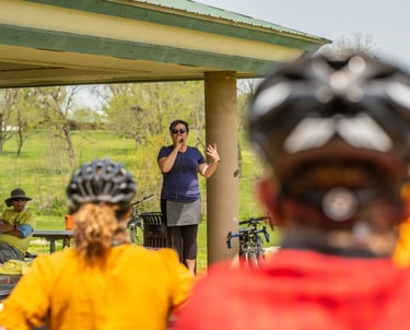 Mayor Barbara Buffaloe speaking into a microphone before a group of people wearing bike helmets