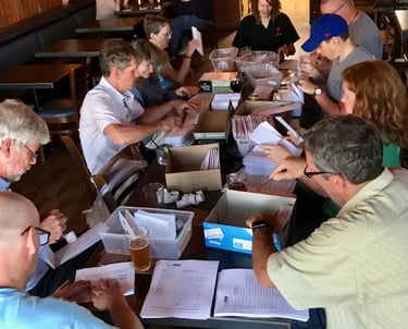 A group of people around a table covered in envelopes working
