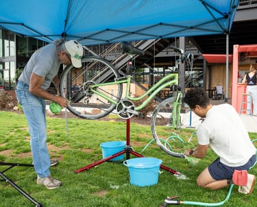 Two people cleaning a mounted bike with sponges