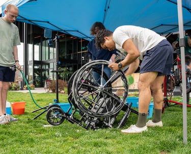 Person washing a wheelchair wheel with a sponge and suds