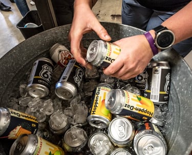 Hands grabbing a beer from a bucket of beers on ice