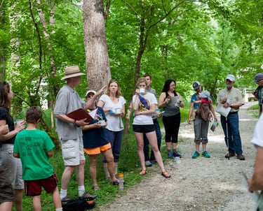 A circle of people stopped on a trail listening to the guide speak