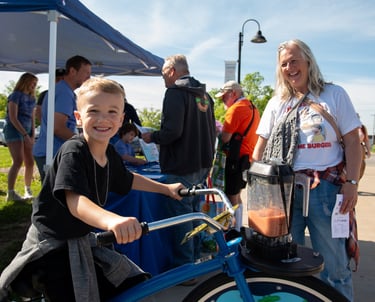 Child powering the blender bike with their adult nearby smiling