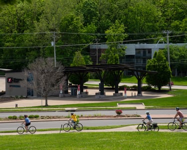 People biking on a sidewalk near a road