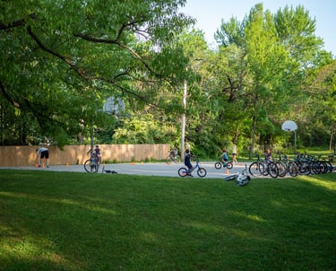 Kids completing a biking course around cones in a park