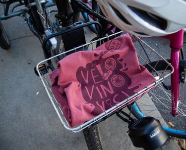 Photo of the Velo Vino Vici event T-Shirt, folded up sitting in a bike basket