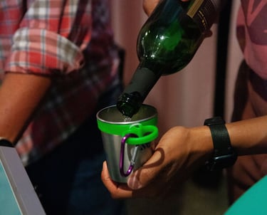 Hands pouring white wine into a small cup