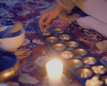 a close up of sungka divination tool game with a woman's hand moving shells