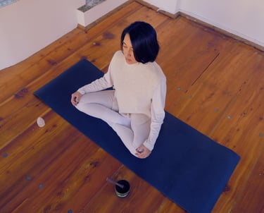 a woman pictured from above in a meditative state with a selenite and tibetan bowl in front