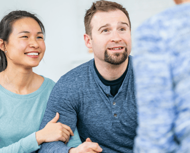 couple smiling and wearing blue shirts attending couples counselling calgary