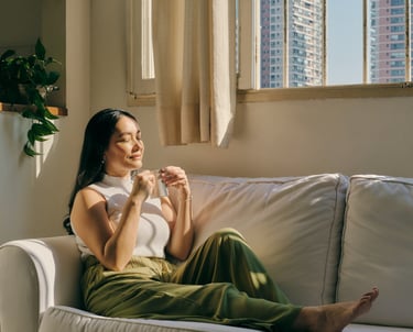 a woman sitting on a couch with a cup of coffee relaxing