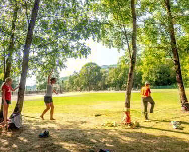 Deux adultes et une enfant pratique la slackline dans un parc
