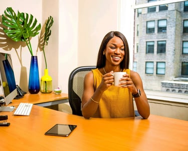Woman at desk smiling and holding a mug