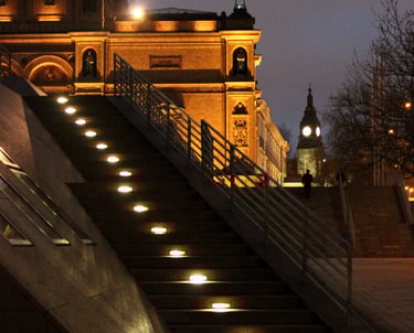 a lit staircase leading up to a building with a clock tower in the background