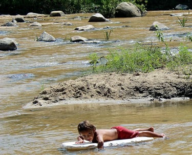 a young boy laying on a surfboard in the waters of Puerto Vallarta