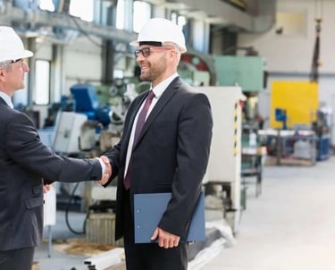 two men shaking hands in a factory
