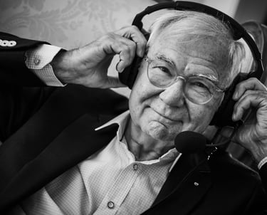ein Mann im Anzug und mit Brille trägt ein Headset
