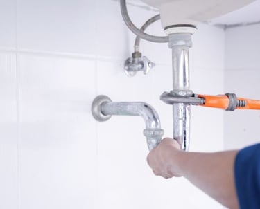 a plumber in a blue shirt is holding a wrenCH.