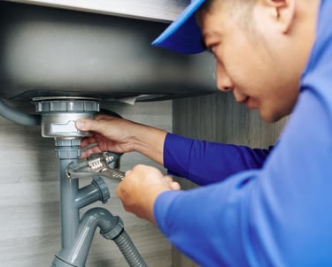 a  bc plumber in a blue shirt is fixing a sink