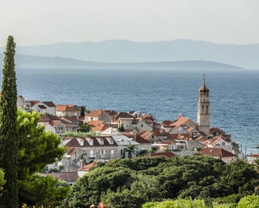 Panoramic view of Sutivan with red-tiled roofs and a historic church tower by the Adriatic Sea.
