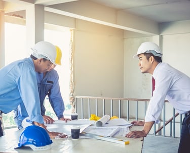 two men in hard hats and hard hats are standing in front of a table