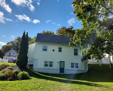 a house with a white house with a blue sky and clouds