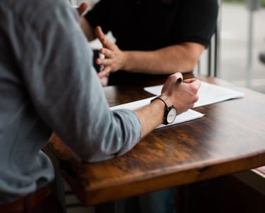 two people talking paper and pen on table