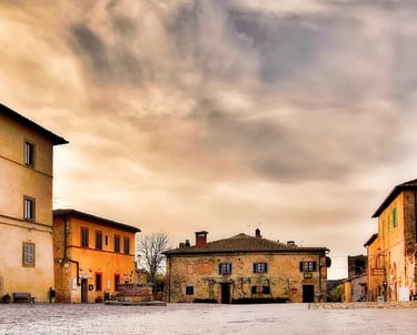 Piazza Roma in Monteriggioni, Tuscany – medieval square with stone buildings and warm sunset sky ins