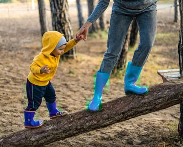 a woman in a yellow raincoat and blue boots is holding a child's