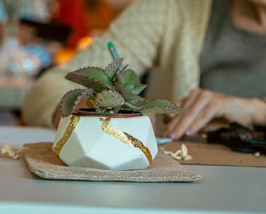 a woman sitting at a table with a plant in a potted potted with