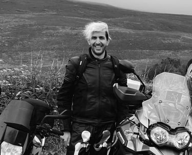 A young rider called Dan stood behind his motorcycle in a countryside landscape